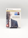 PS4 Steelbook Edition of The Complete First Season of Hitman, shown in its shrink wrap packaging on a small display stand against a light gray background.